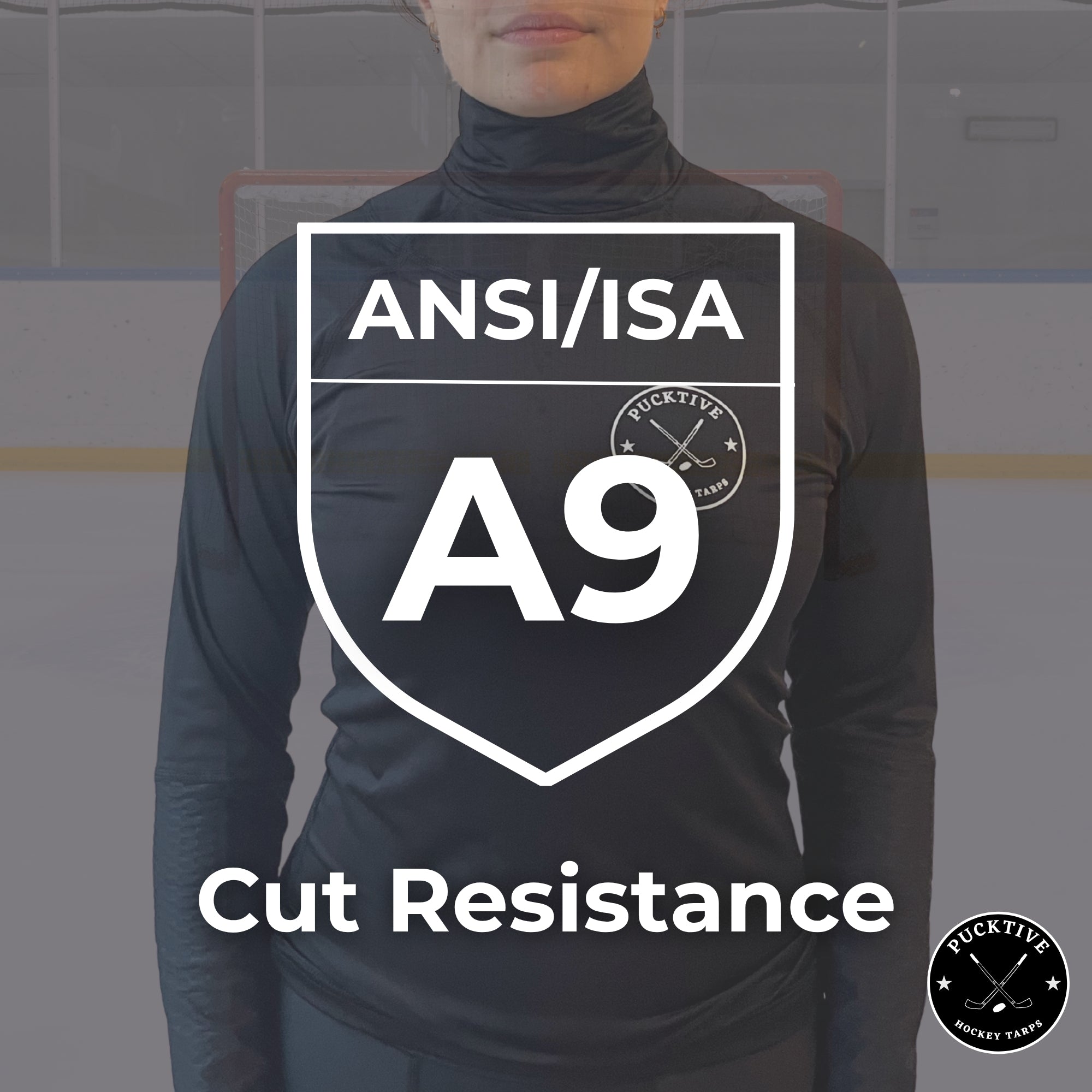 Person wearing a black long-sleeve shirt with ANSI/ISA A9 cut resistance certification on a blurred hockey rink background.